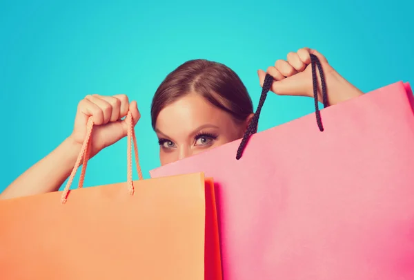 Chica morena con bolsas de compras en backgorund azul . —  Fotos de Stock
