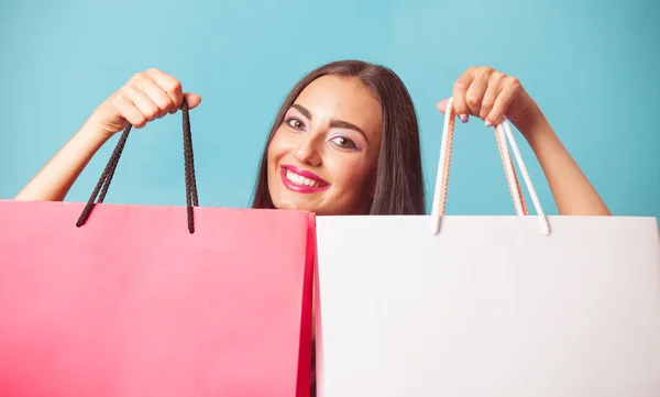 Chica morena con bolsas de compras en backgorund azul . —  Fotos de Stock