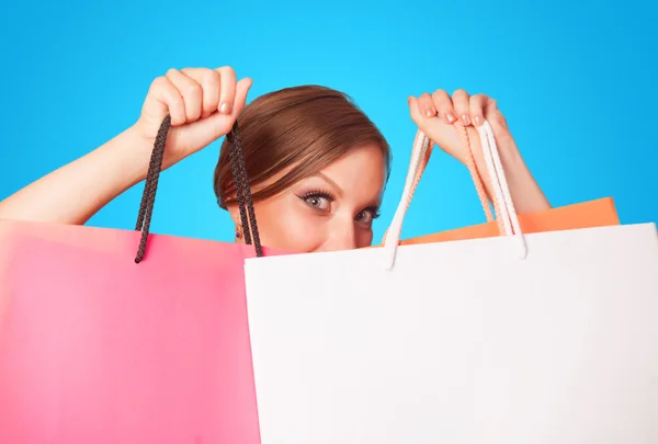 Chica morena con bolsas de compras en backgorund azul . — Foto de Stock