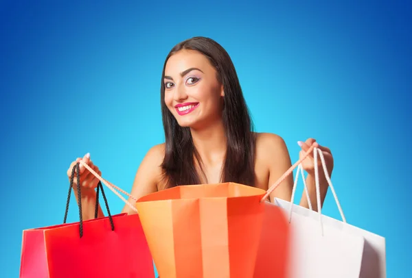 Chica morena con bolsas de compras en backgorund azul . —  Fotos de Stock