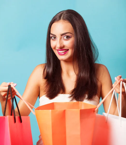 Brunette girl with shopping bags on blue backgorund. — Stock Photo, Image