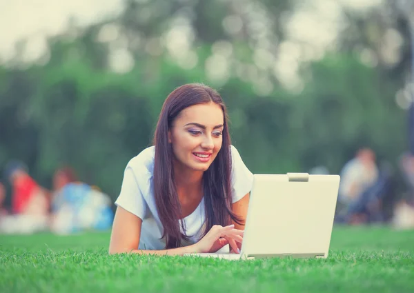 Brunette girl with notebook on green grass in the park. — Stock Photo, Image
