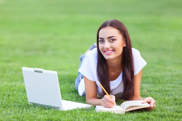 노트북 및 공원에서 푸른 잔디에도 서와 갈색 머리 여자. — 스톡 사진