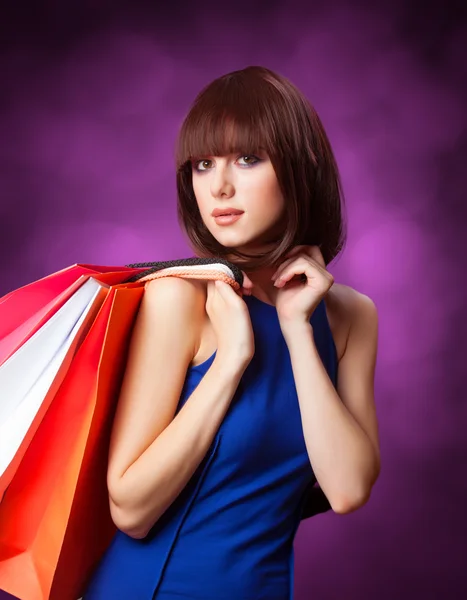 Bruna ragazza con shopping bags su sfondo viola . — Foto Stock