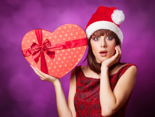 Girl in xmas hat with gift box on violet background. — Stock Photo, Image