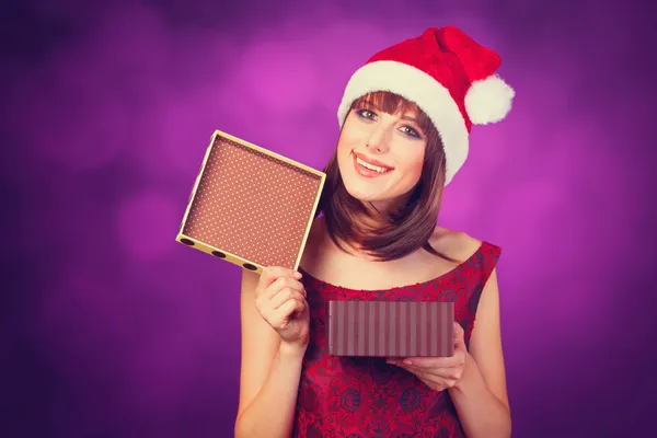 Chica en sombrero de Navidad con caja de regalo sobre fondo violeta . —  Fotos de Stock