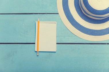 defter kalem ve mavi ahşap masa üzerine şapka ile