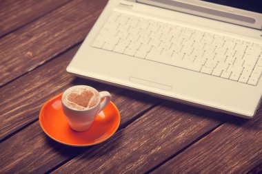 kahve kalp şekli ve ahşap masa üstünde defter.