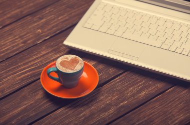 kahve kalp şekli ve ahşap masa üstünde defter.