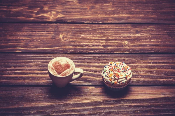 Taza de café y magdalena en mesa de madera . — Foto de Stock