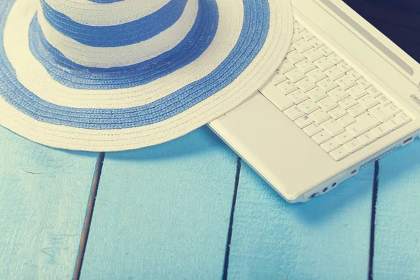 Laptop e chapéu na mesa de madeira azul . — Fotografia de Stock