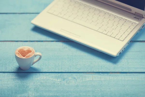 Fincan kahve ve mavi ahşap masa üstünde laptop. — Stok fotoğraf