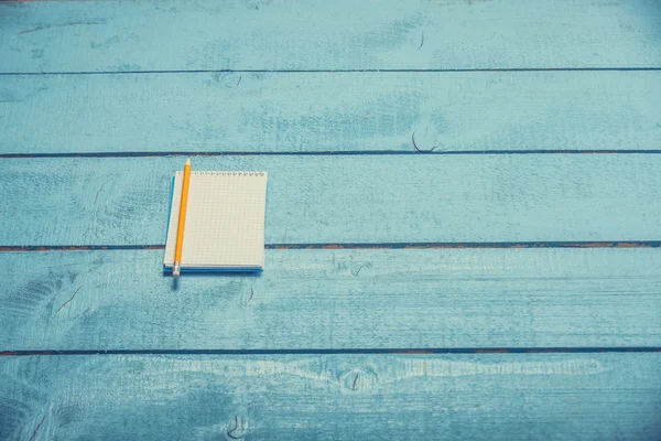 Notebook z ołówka na niebieskim drewnianym stołem — Stockfoto