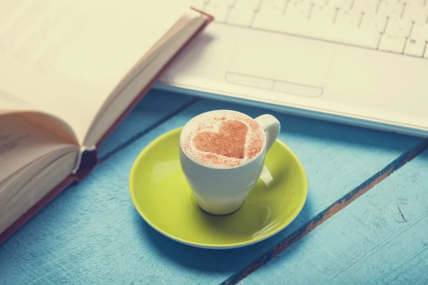 Kaffeetasse mit Laptop und Buch auf blauem Holztisch. — Stockfoto