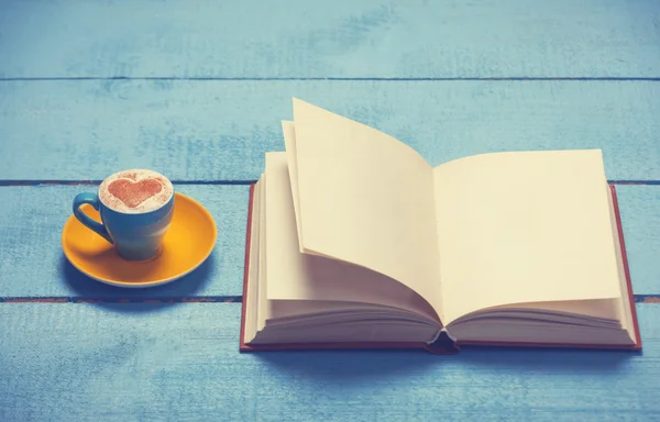 Cup of coffee with book on blue wooden table. — Stock Photo, Image