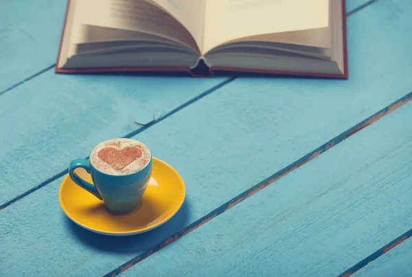 Tazza di caffè con libro su tavolo di legno blu . — Foto Stock