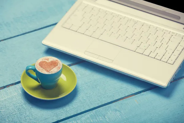 Kopp kaffe och laptop på blå träbord. — Stockfoto