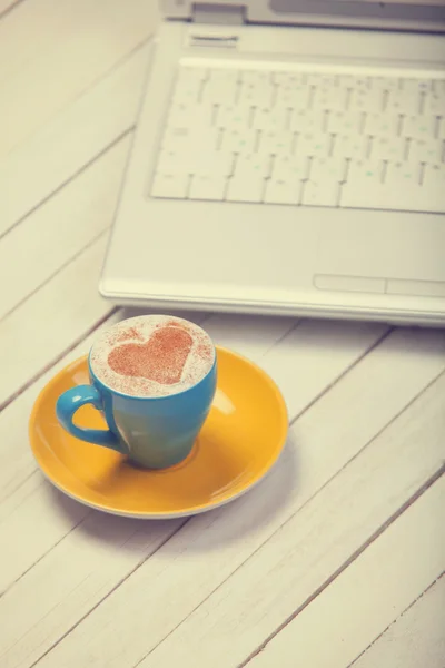 Kopp kaffe med hjärta form och notbook på träbord. — Stockfoto