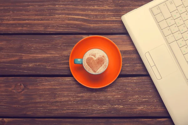 Cup of coffee with heart shape and notebook on wooden table. — Stock Photo, Image