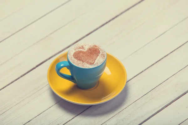 Kopje koffie met hartvorm op houten tafel. — Stockfoto