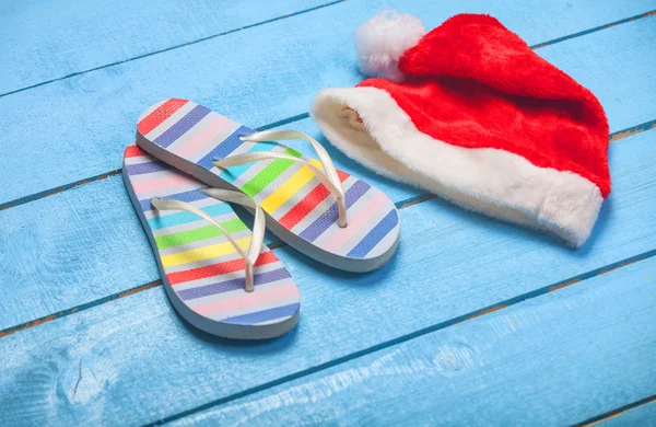 Zapatillas de playa y sombrero de Navidad en madera azul —  Fotos de Stock