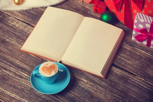 Cup of coffee with heart shape, book and christmas gifts. — Stock Photo, Image