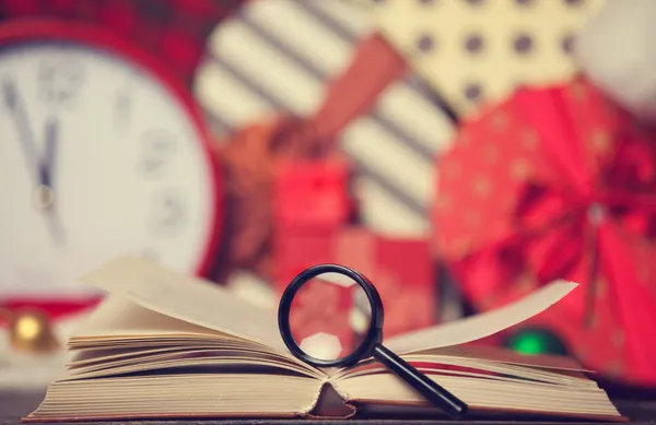 Loupe y libro sobre fondo de regalos de Navidad — Foto de Stock