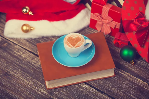 Cup of coffee and book with christmas gifts — Stock Photo, Image