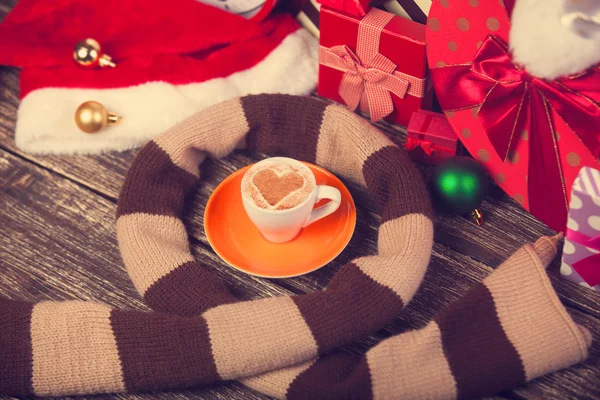 Cup of coffee with heart shape, scarf and christmas gifts. — Stock Photo, Image