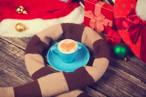Cup of coffee with heart shape, scarf and christmas gifts. — Stock Photo, Image