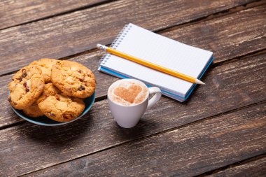 Kahve, kalem ve defterli kurabiye ve kupa..