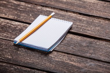 defter ve kalem tahta masada..