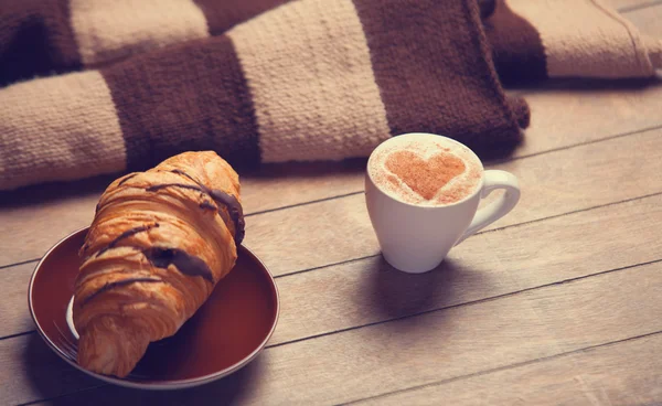 Französisches Croissant und eine Tasse Kaffee auf einem Holztisch — Stockfoto