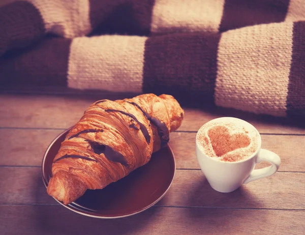 Croissant francés y taza de café en una mesa de madera — Foto de Stock