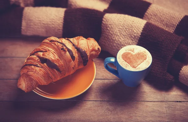 French croissant and cup of coffee on a wooden table — Stock Photo, Image
