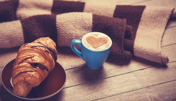 Croissant francés y taza de café en una mesa de madera —  Fotos de Stock