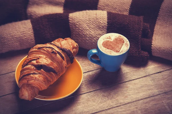 Croissant francés y taza de café en una mesa de madera —  Fotos de Stock