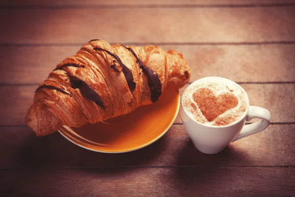 Frans croissant en kopje koffie op een houten tafel — Stockfoto