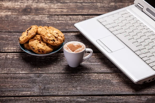 Kurabiye ve kahve ile ahşap masa üstünde laptop. — Stok fotoğraf