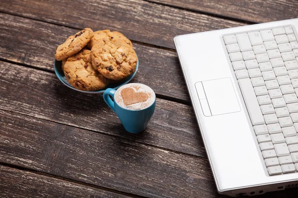 Cookie 和杯咖啡与木制的桌子上的笔记本电脑. — 图库照片