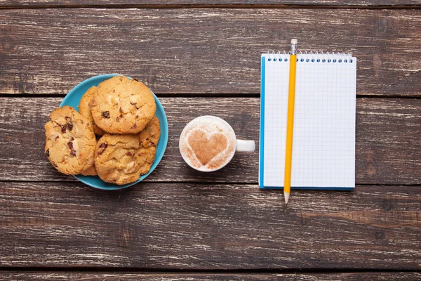 Koekje en kopje met koffie, potlood en notebook. — Stockfoto
