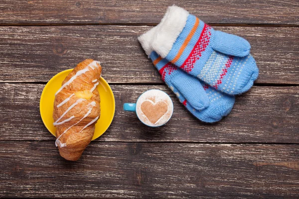 Handskar och kopp kaffe på träbord. — Stockfoto