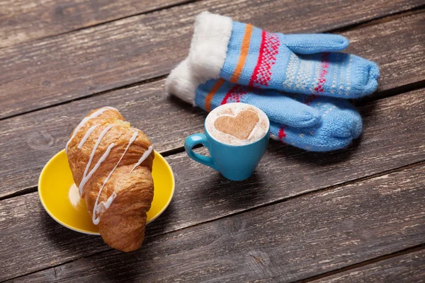 Handschoenen en kopje koffie op houten tafel. — Stockfoto