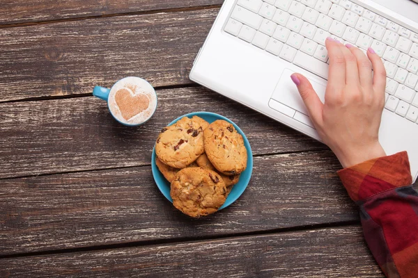 Cookie en vrouwen hand met laptop. — Stockfoto
