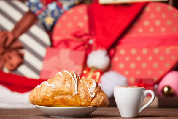 Šálek kávy a croissantu na vánoční pozadí. — Stock fotografie