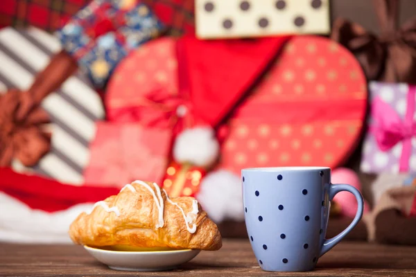 Tasse Kaffee und Croissant auf weihnachtlichem Hintergrund. — Stockfoto