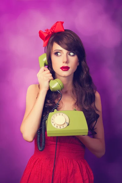 Schöne brünette Mädchen mit Telefon auf violettem Hintergrund. — Stockfoto