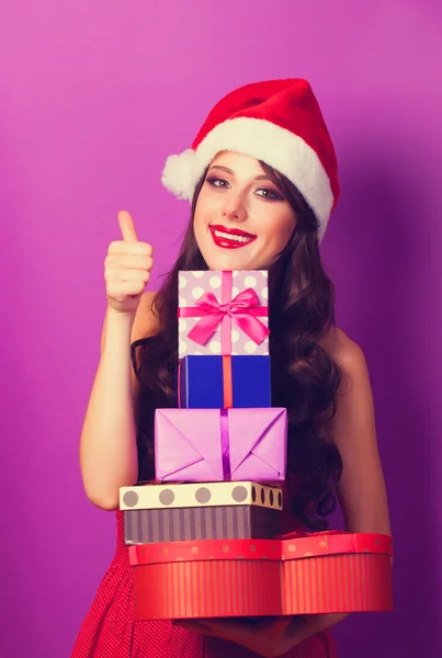 Beautiful brunette girl in christmas hat with gifts  on violet b — Stock Photo, Image