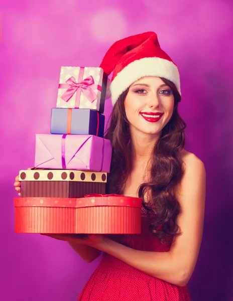 Beautiful brunette girl in christmas hat with gifts  on violet b — Stock Photo, Image