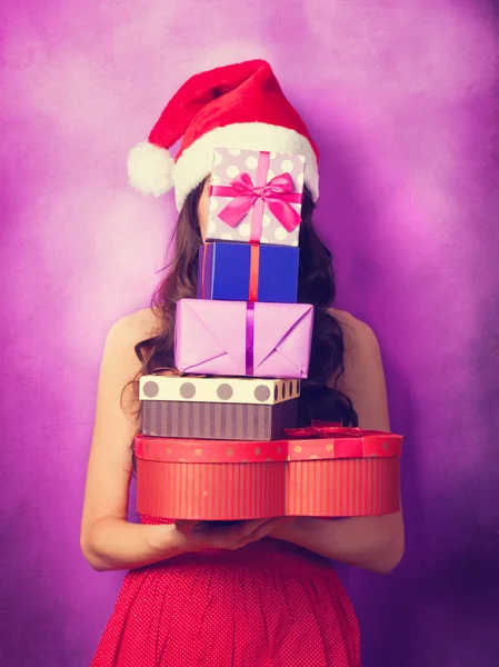 Beautiful brunette girl in christmas hat with gifts  on violet b — Stock Photo, Image